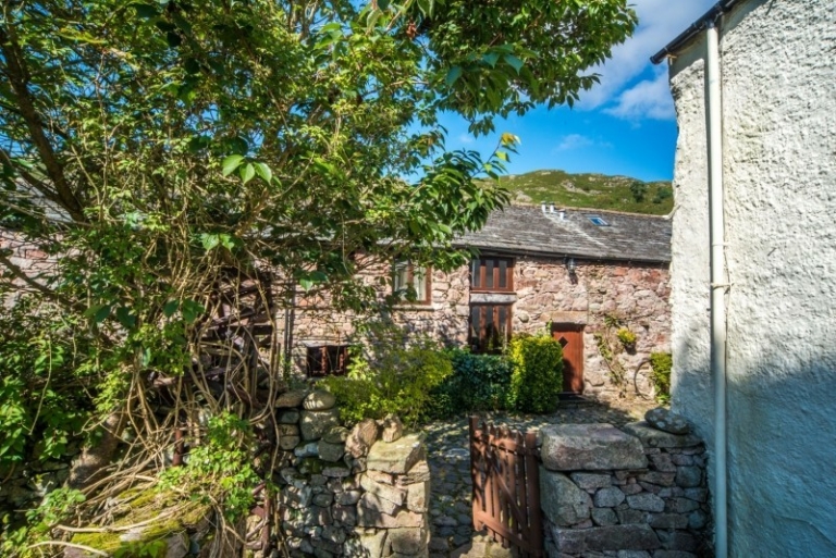 Hardknott Cottage - view of the front door surrounded by beautiful Eskdale pink granite with fells rising above and amazing hikes on the doorstep!